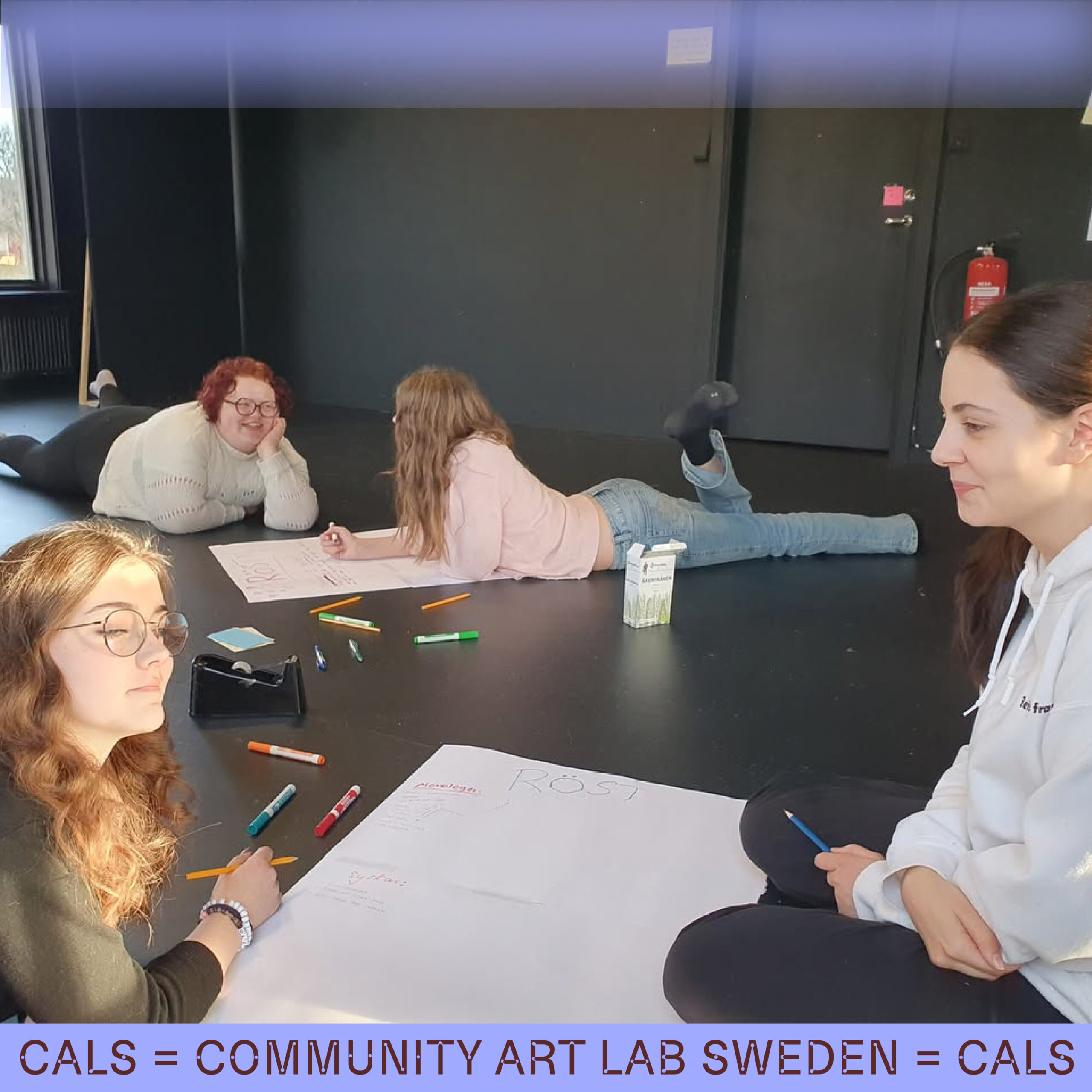 Fyra tjejer ligger på golvet och skriver på temat "Röst"